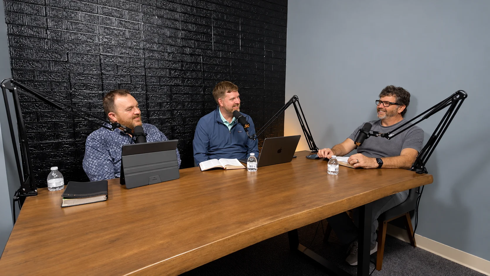 Pastor Mark, Pastor Jonathan, and Doug laughing around the table in the podcast studio