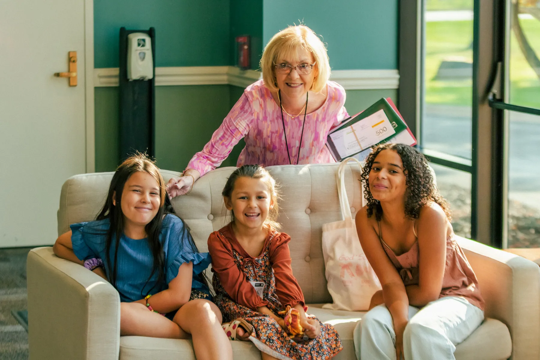 A greeter smiling with three girls on a lobby couch