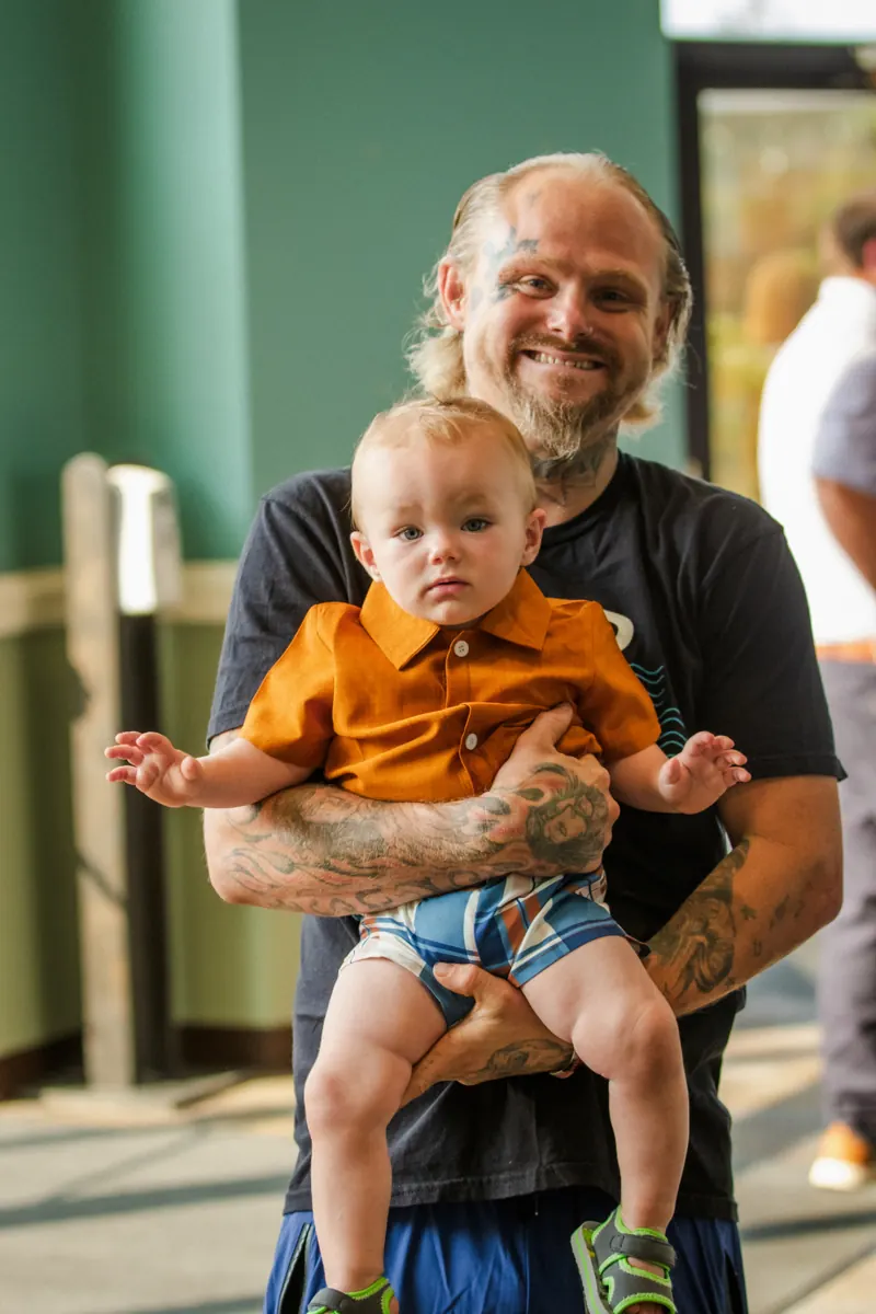 A dad smiling while holding his young son in the lobby