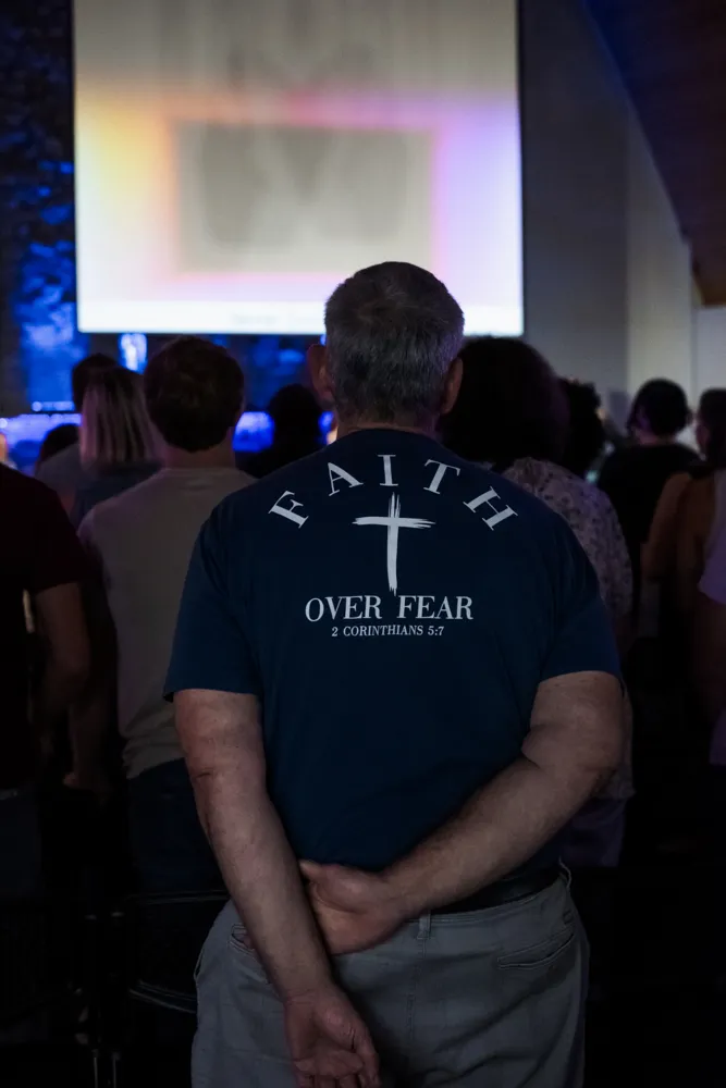 A man in a Faith Over Fear shirt during worship