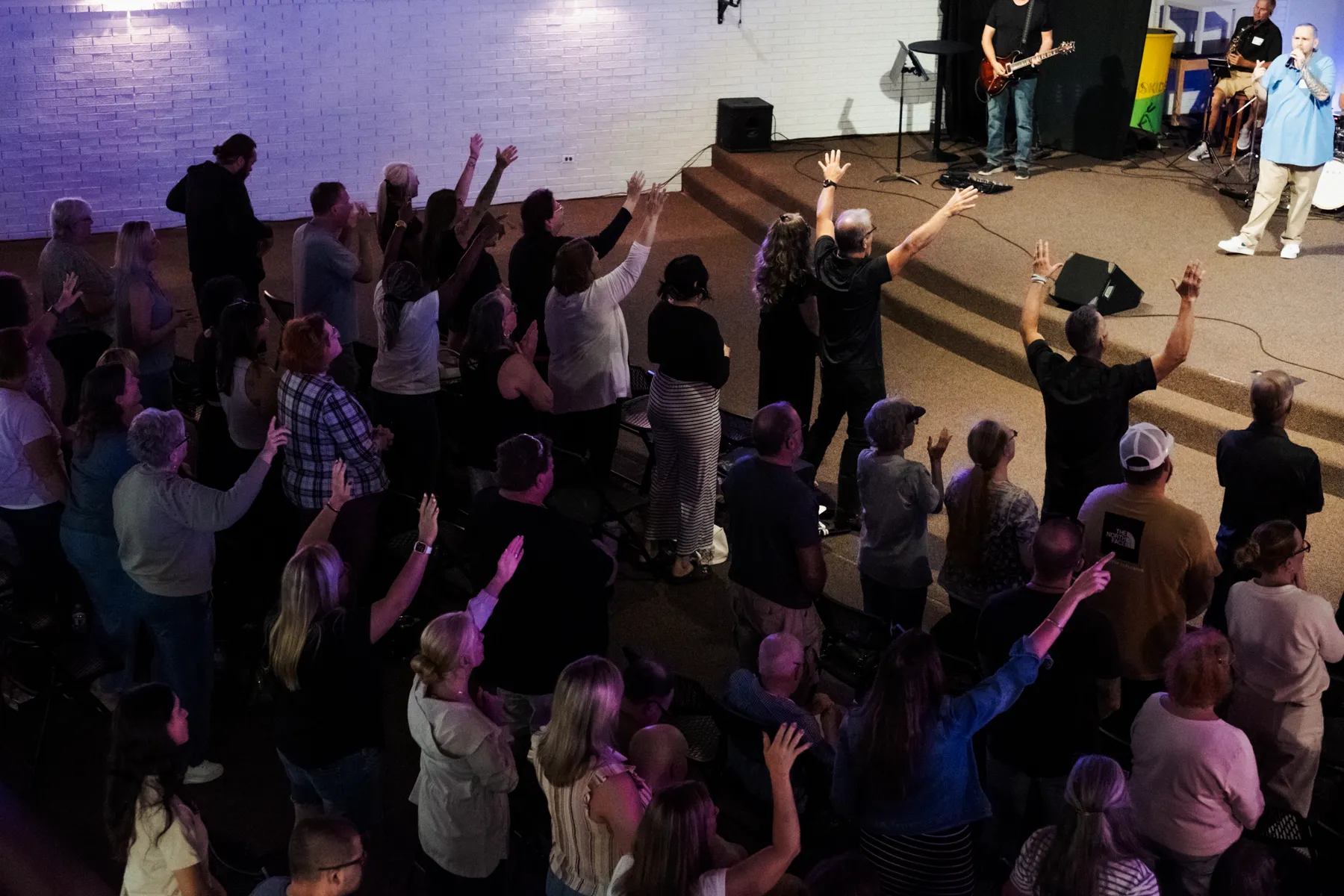 A full room worshipping with hands raised at Recovery Alive