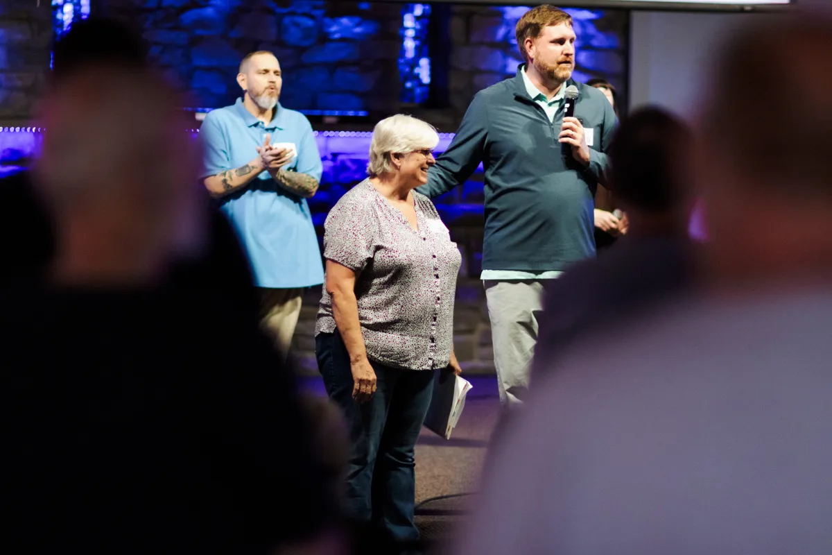 A woman sharing her testimony on stage with Recovery Alive leaders