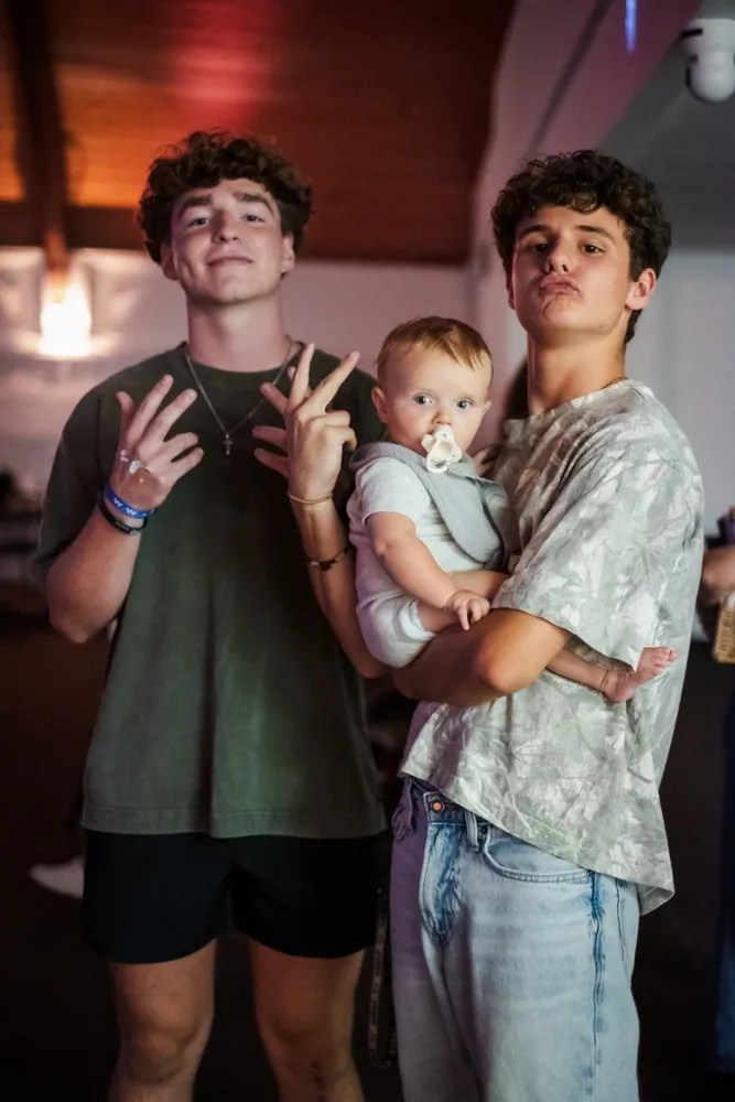 Two students goofing around with a baby at youth night