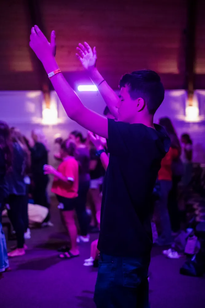 A student worshipping with hands raised
