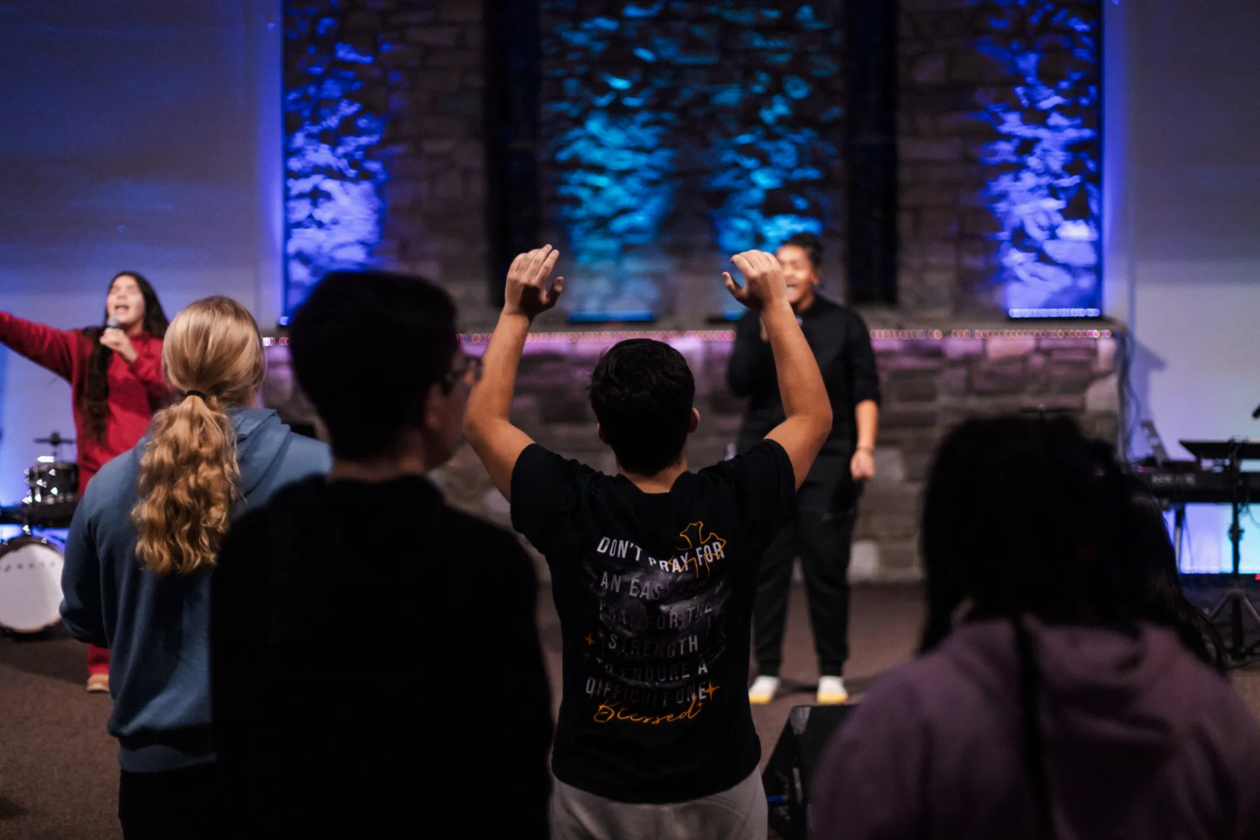 Students worshipping with hands raised at youth night